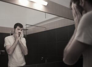 رجل ينظر لانعكاسه في المرآة